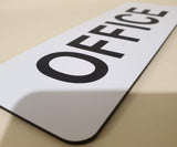 White sign with Black 'OFFICE' text on a beige surface