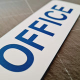 White sign with blue 'OFFICE' text on a tiled floor