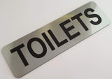 Silver sign with Black 'TOILETS' text on a white background
