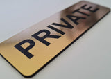 Gold sign with black text 'PRIVATE' on a white surface