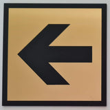 Black engraved arrow on a gold square acrylic sign