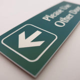 Evergreen acrylic sign with white engraved arrow and text on a light gray background