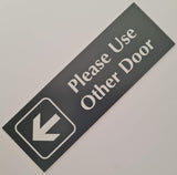 Rectangular Smoke Grey acrylic sign with white engraved text 'Please Use Other Door' and an arrow