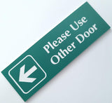 Celadon Green acrylic sign with white engraved text and arrow on a white background