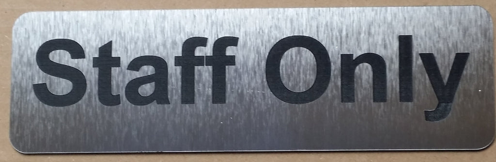 Silver sign with 'Staff Only' Black text on a plain background