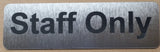 Silver sign with 'Staff Only' Black text on a plain background