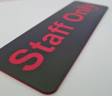 Black sign with red 'Staff Only' text on a gray background