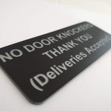 Black sign with silver text on a white background