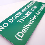 Green sign with white text indicating 'No Door Knockers Thank You (Deliveries Accepted)' on a white background