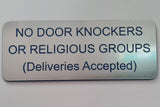 Plastic sign on a door indicating 'No door knockers or religious groups, deliveries accepted'.