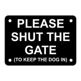 A black acrylic sign with the text 'PLEASE SHUT THE GATE (TO KEEP THE DOG IN)' in white capital letters, with four holes for mounting.