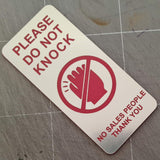 Silver Sign with Red text 'Please do not knock, no sales people thank you'.