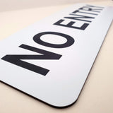 White sign with Black text 'NO ENTRY' on a beige surface