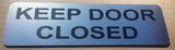 Silver acrylic sign with Black text 'KEEP DOOR CLOSED'
