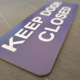 Purple acrylic sign with white text 'KEEP DOOR CLOSED'