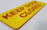 Yellow acrylic sign with red text 'KEEP DOOR CLOSED'