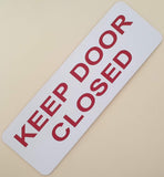Rectangular white acrylic sign with red text 'KEEP DOOR CLOSED'