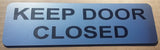 Silver sign with Black Text 'KEEP DOOR CLOSED'