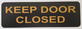 Black acrylic sign with gold text 'KEEP DOOR CLOSED'