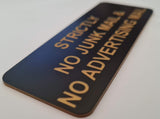 Black acrylic sign with gold engraved text 'Strictly No Junk Mail & No Advertising' on a white background