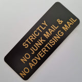 Black acrylic sign with gold engraved text on a white background