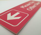 Red acrylic sign with white engraved arrow and text