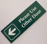 Evergreen acrylic sign with white engraved text and arrow pointing left on a light gray background