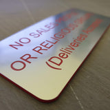 Silver acrylic sign with red engraved text on a reflective surface