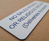 Sign on a door indicating no salespeople, religious groups, or deliveries are accepted.