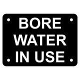 Black acrylic sign with white engraved text 'BORE WATER IN USE' on a white background